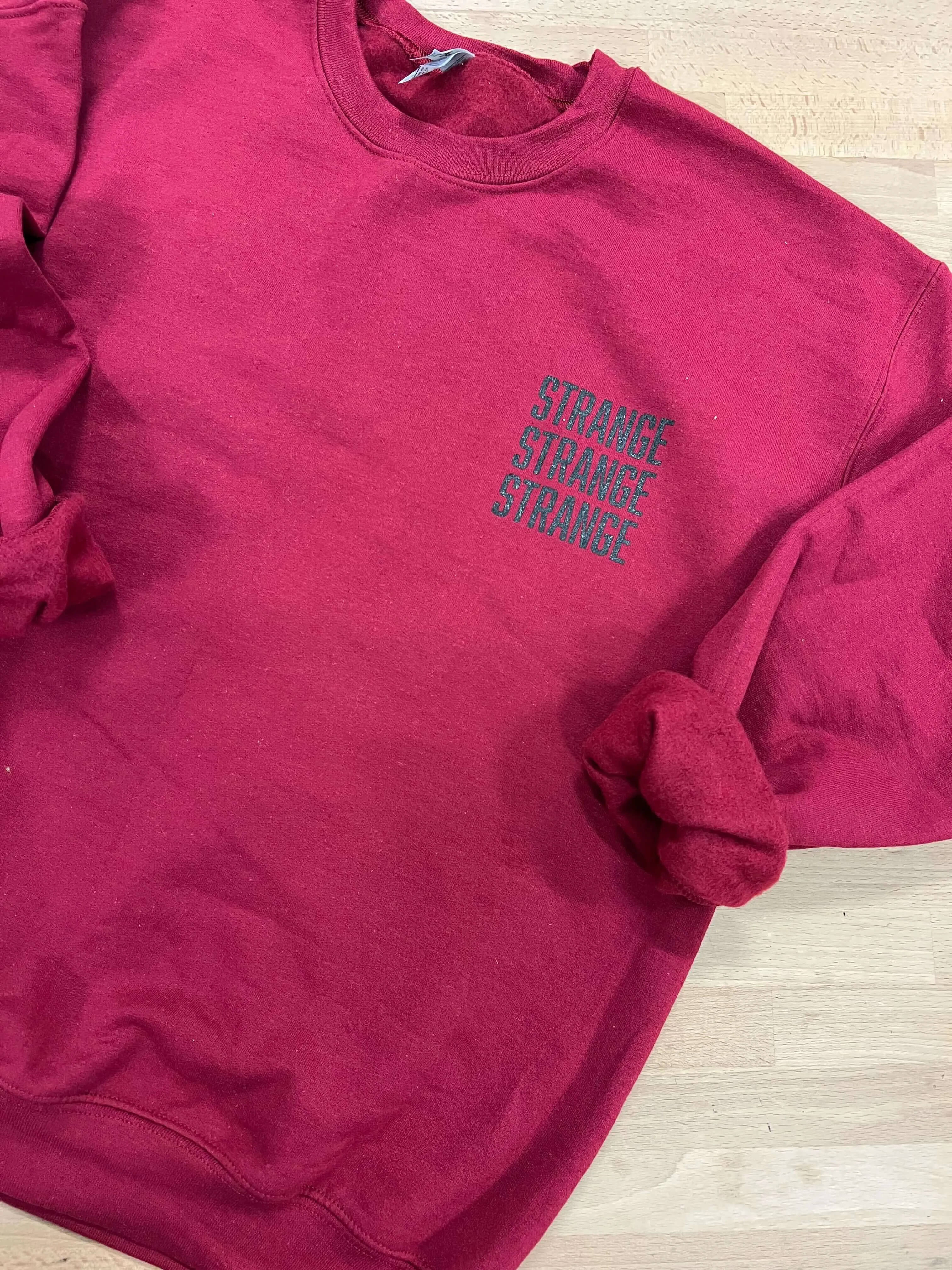 "Strange Strange Strange" small logo crewnecks