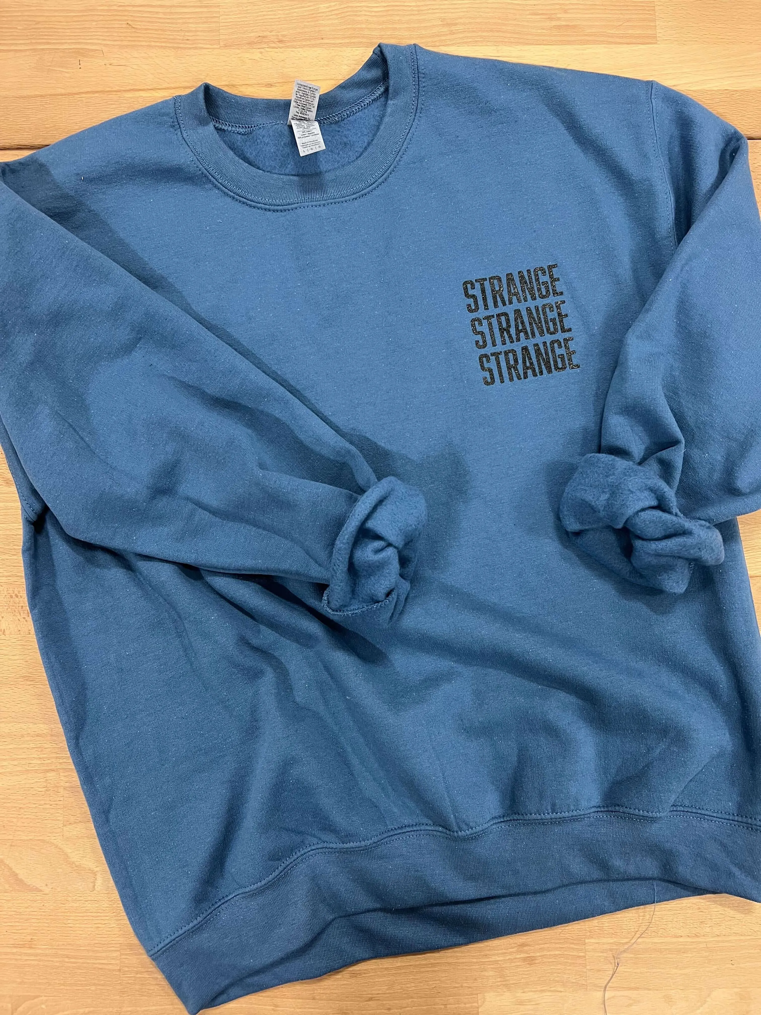 "Strange Strange Strange" small logo crewnecks